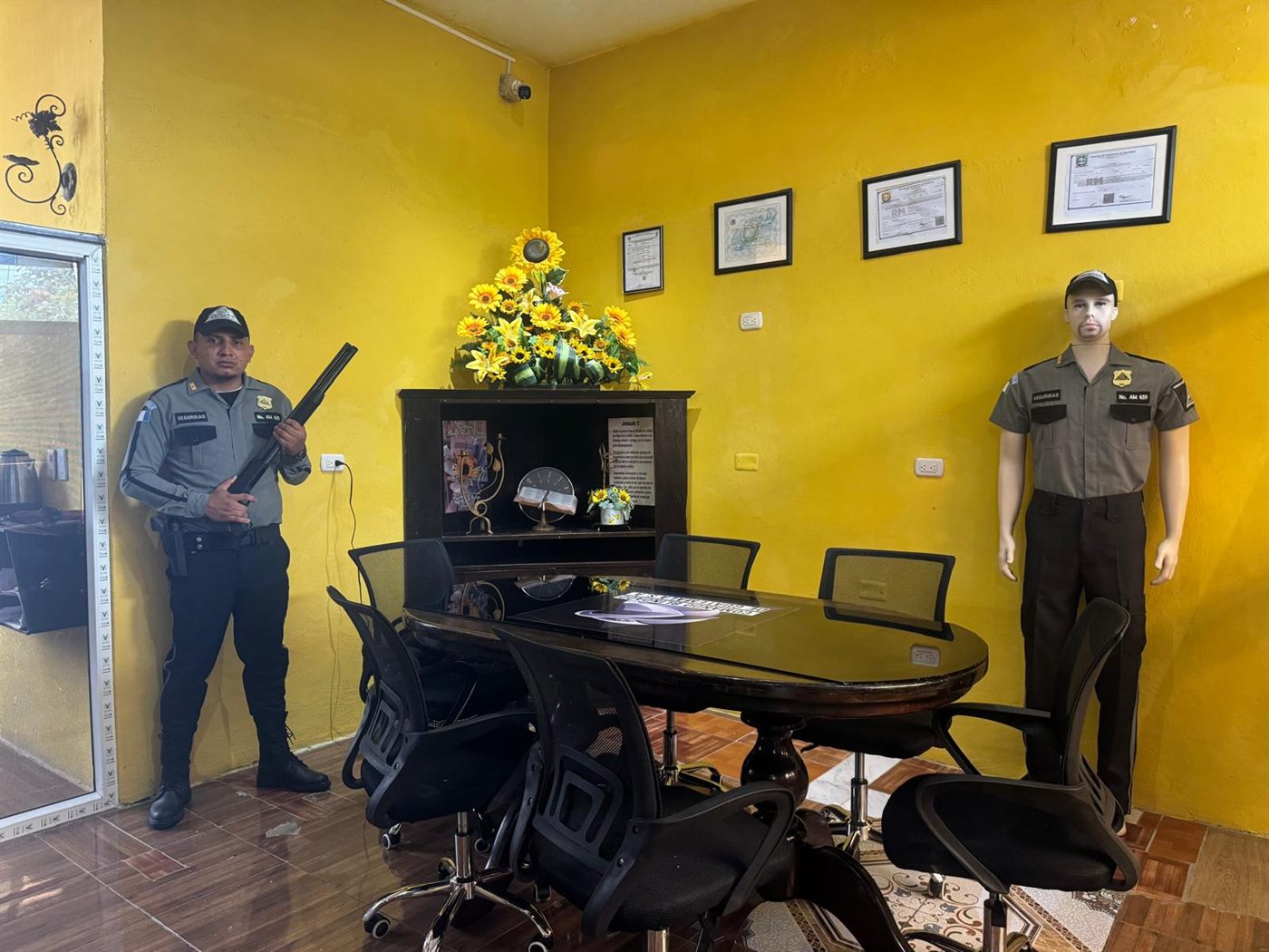 Sala de juntas de Comando Blindado de Guatemala en Coatepeque con las licencias de operación enmarcadas y agente uniformado